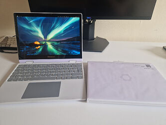 lavender fw12 opened on a desk next to a second one still wrapped in protective paper