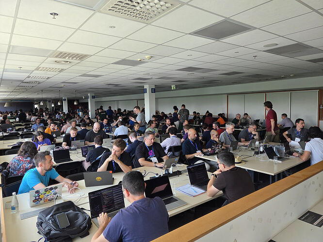 People discussing and working on laptops in the EuroPython sprint room.