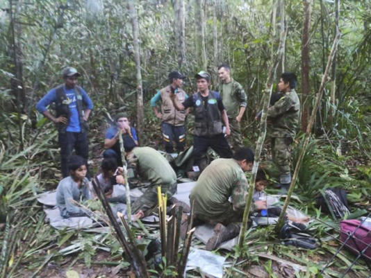 In this photo released by Colombia's Armed Forces Press Office, soldiers and Indigenous men tend to the children found in the Amazon jungle. ©Colombia's Armed Force Press Office via AP