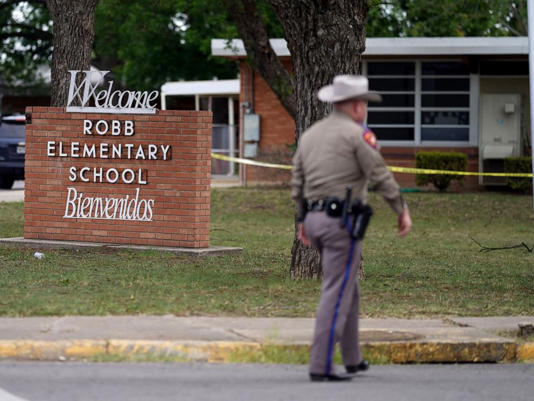 In this May 24, 2022, file photo, an officer walks outside of Robb Elementary School in Uvalde, Texas.