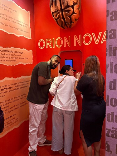 Three people are interacting with an exhibit in a red room labeled "ORION NOVA," featuring a large brain model and informational text on the walls. (Captioned by AI)